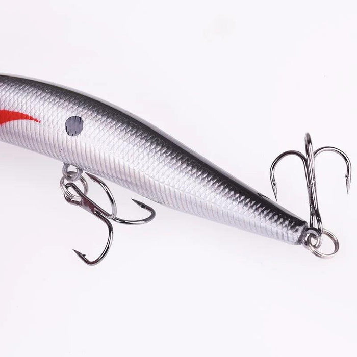 A side view of the silver fishing lure, focusing on the attached treble hooks and the lure's textured, reflective surface.