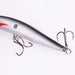 A side view of the silver fishing lure, focusing on the attached treble hooks and the lure's textured, reflective surface.