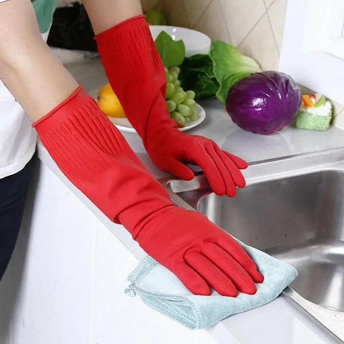 A man wears red cleaning gloves and cleans the sink with a blue rag with purple cabbage, lettuce, lemon and grapes appearing in the background.