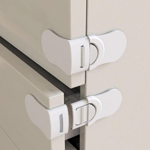 Two white safety locks installed on adjacent drawers of a light-colored cabinet, showing the lock mechanism that secures the drawers from being opened.