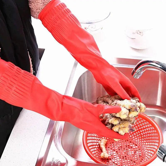 A person wears red cleaning gloves and holds food over the sink with a red strainer inside.