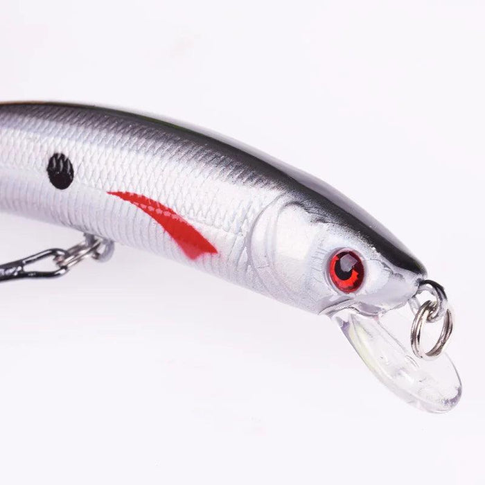 A close-up view of a silver fishing lure with red eyes and a red stripe detail near the head, highlighting the realistic design.