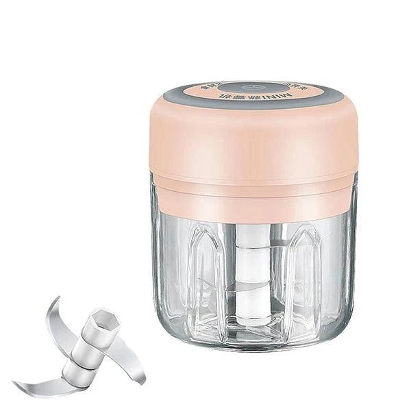 A close-up of a food chopper with a pink lid, showcasing the blade and clear container.