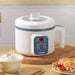 A white multi-functional cooker with digital controls, set on a table with a bowl of rice and a plate of seafood.