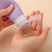 Purple ribbed silicone travel bottle dispensing a gel-like substance into a hand, showcasing the clear flip-top cap. This 3 fl oz container is ideal for easily squeezing out toiletries such as gels and lotions, ensuring no-spill travel convenience.