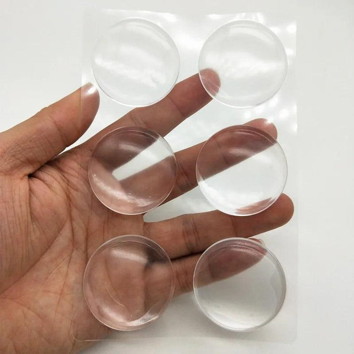 A hand holding a transparent sheet with six clear silicone protectors, demonstrating the product set.