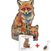 An artistic wooden puzzle depicting a fox family with rich colors and patterns, accompanied by an A4 size box and a keychain.