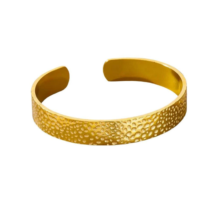 Gold cuff bracelet with a hammered pebble texture, displayed on a white background.