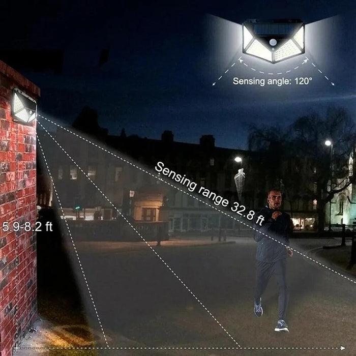 The solar-powered motion sensor light installed on a brick wall, illuminating a wide area at night. The image highlights the sensing angle of 120 degrees and a sensing range of 32.8 feet, showing a man walking within the detection zone.