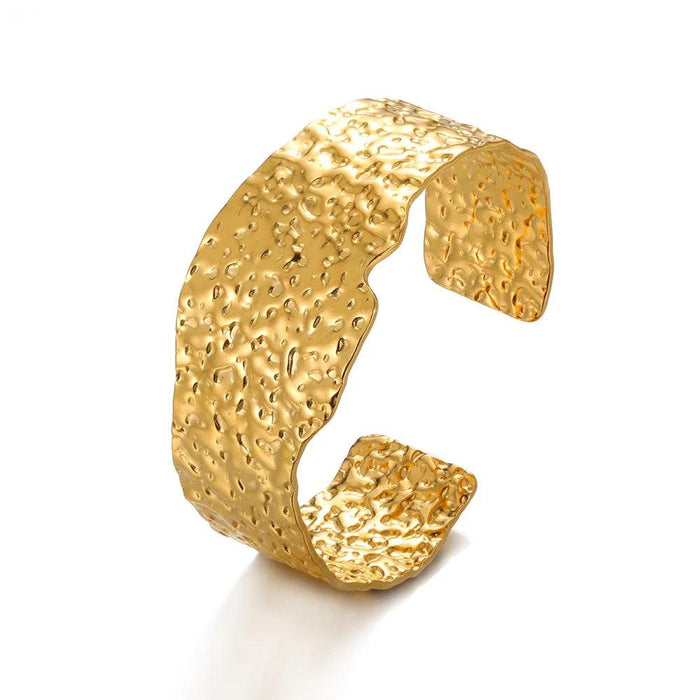 Wide gold cuff bracelet with a hammered texture, displayed on a white background.