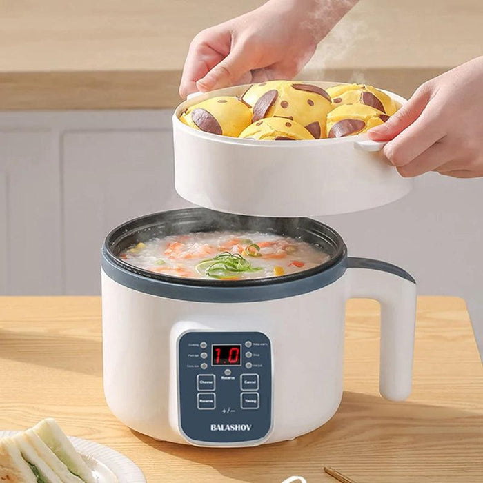 A white multi-functional cooker with digital controls, steaming a pot of soup. A tray with yellow buns is being lifted out from the top.