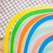 a close-up of several cutting mats stacked together in different colors, including yellow, green, orange, and blue, highlighting the variety of available colors.