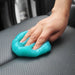 A hand using blue cleaning gel to clean a car seat.