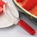 Another view of the slicer with a red handle, positioned beside a plate and a cut watermelon, illustrating its practical application.