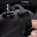 Close-up of a hand attaching a black hook to a car headrest pole.