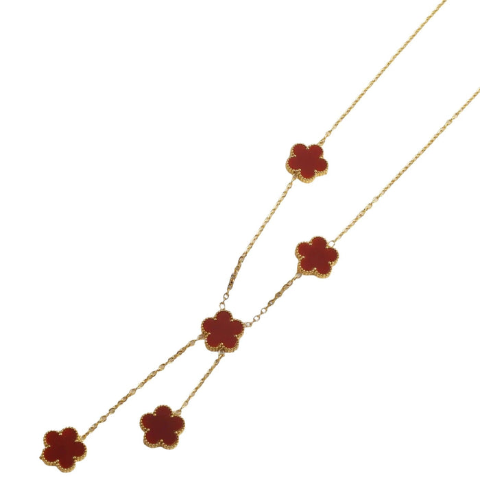 A gold necklace, designed with a flower-shaped pendant with a red center.