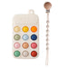 A cream silicone teether resembling a phone keypad with colorful buttons, next to a pacifier clip with a wooden clasp and pink silicone beads.