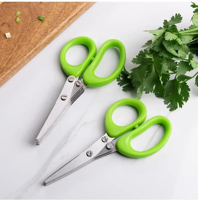 Two green-handled herb scissors placed on a cutting board with fresh herbs.