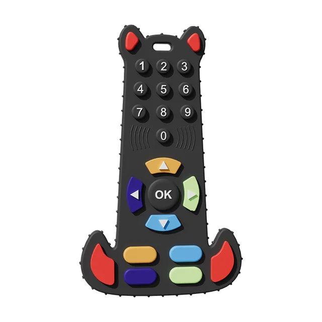 A black silicone teether shaped like a remote control with colorful buttons and red horns.