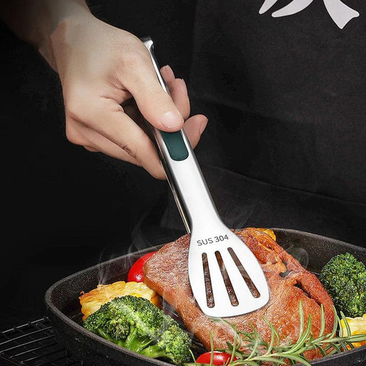 Stainless steel tongs being used to flip a piece of meat in a frying pan with vegetables.