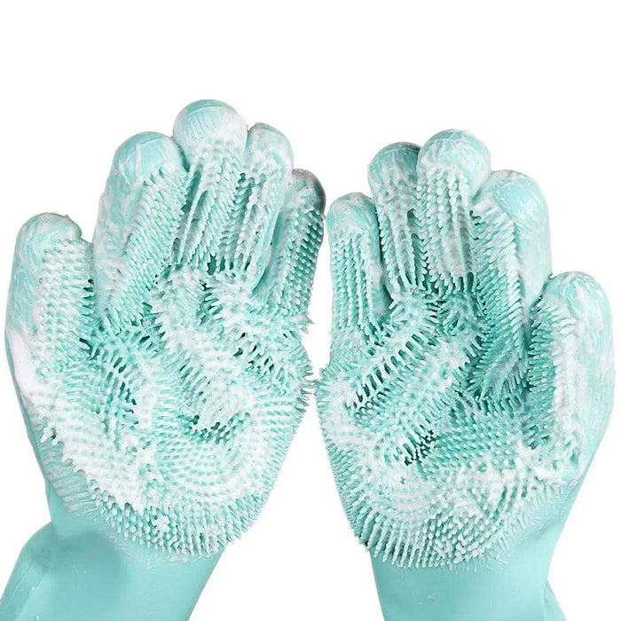 A close-up view of a pair of turquoise silicone cleaning gloves covered in soap suds, highlighting the rubber bristles on the palms and fingers.