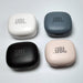 Four closed JBL charging cases in black, white, blue, and pink.