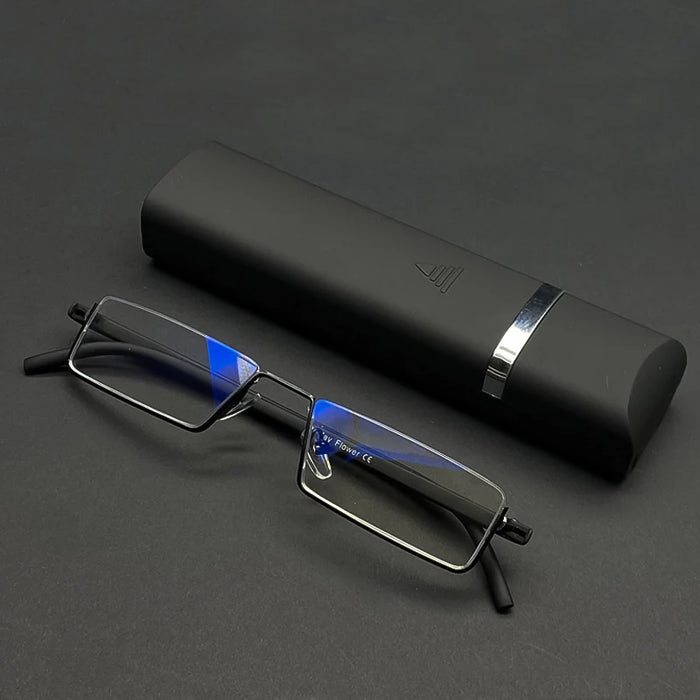 A pair of rectangular eyeglasses with thin, black frames and blue light-filtering lenses is placed next to a sleek, black eyeglass case with a silver accent band. The glasses and case are displayed on a black surface.