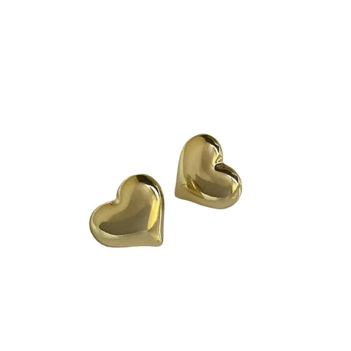 a pair of gold heart-shaped stud earrings against a white background. The earrings have a smooth, reflective surface, giving them a polished and elegant look.