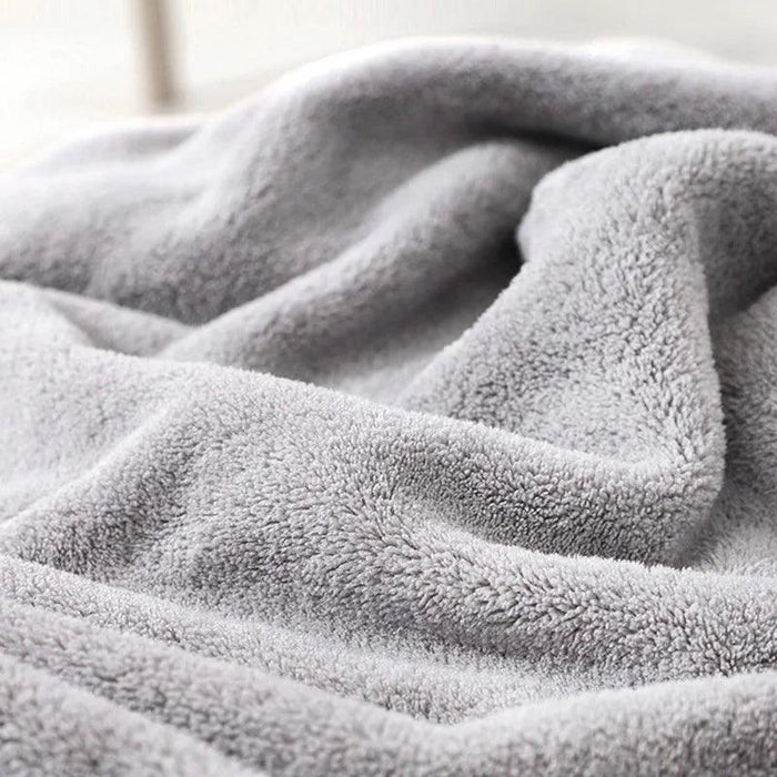 A close-up image showing the texture of a grey, plush baby towel. The material looks soft, fluffy, and comfortable, suitable for a baby's delicate skin.