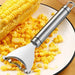 A stainless steel corn peeler is placed on a plate with a corn cob and scattered corn kernels. The peeler has a sleek handle and a curved blade designed to remove kernels efficiently.