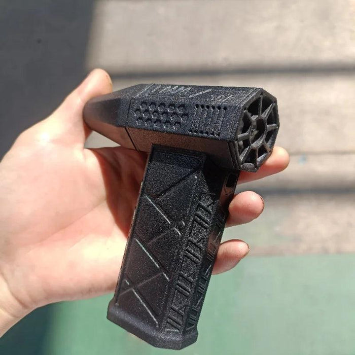 A close-up image of a black handheld blower with a textured grip, being held in a person's hand. The blower has a unique geometric design and a star-shaped nozzle.