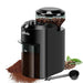 A sleek, black electric coffee grinder with a transparent bean hopper filled with coffee beans. The grinder has a simple on/off button and a grind size adjustment dial. Ground coffee is spilling out of the collection container.