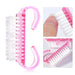 a pink nail brush with white bristles. The brush has a double-ended design with hooks on each end. Inset images highlight the brush in use, demonstrating its effectiveness for cleaning nails and detailing its bristle arrangement.