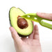 A person using a green avocado slicer to remove the pit from an avocado.