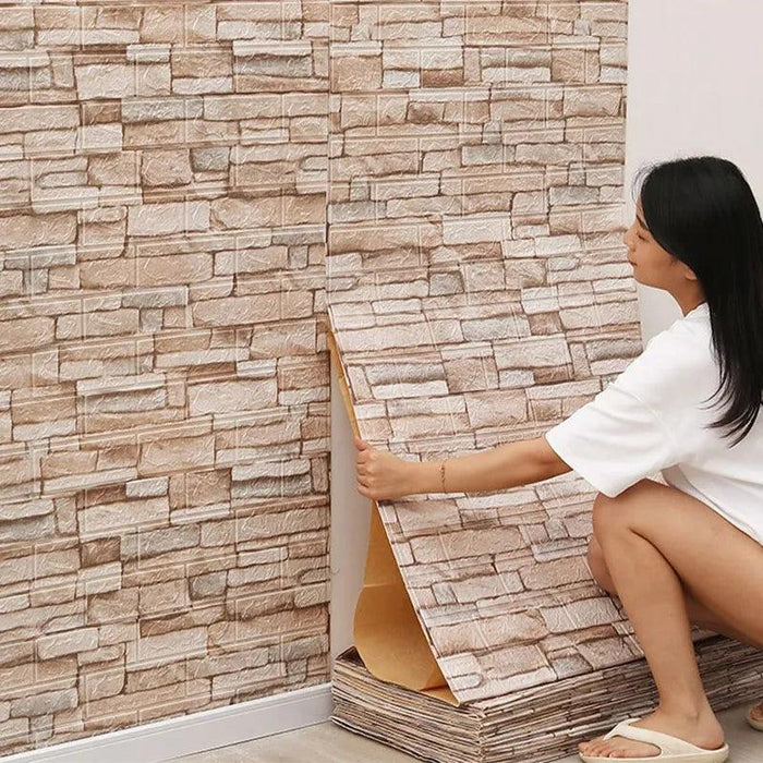 A person applying a wall panel with a stacked stone design in shades of beige and white.