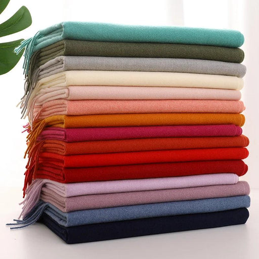 a stack of scarves in various colors including turquoise, olive green, gray, cream, pink, orange, red, and navy blue.