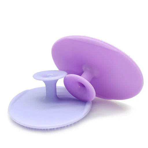 Two purple silicone scrubbers with suction cups, one upright and the other lying flat, showcasing the product's flexibility and texture.