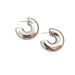 a pair of chunky, crescent-shaped silver hoop earrings. These earrings have a smooth and highly reflective surface, highlighting their contemporary style.