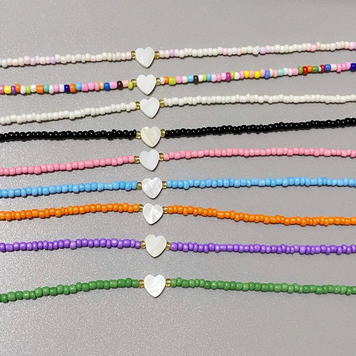  Colorful beaded bracelets, each adorned with a small white heart charm, are arranged neatly in a row.