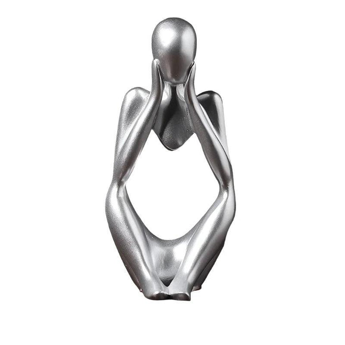 Silver minimalist abstract sculpture of a figure sitting with hands placed on either side of the head.