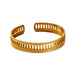 Gold cuff bracelet with rectangular cutouts and a beaded edge, displayed on a white background.