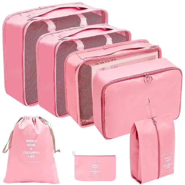 Pink travel organizer set featuring three mesh packing cubes, a drawstring bag, a toiletry bag, and a small pouch, all coordinated with the inspirational message 'WISH U HAVE A COLORFUL LIFE'. Ideal for systematic packing and organization. Display on white background.