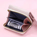 Open beige wallet with a zippered compartment, showing cash inside, on a pink background.