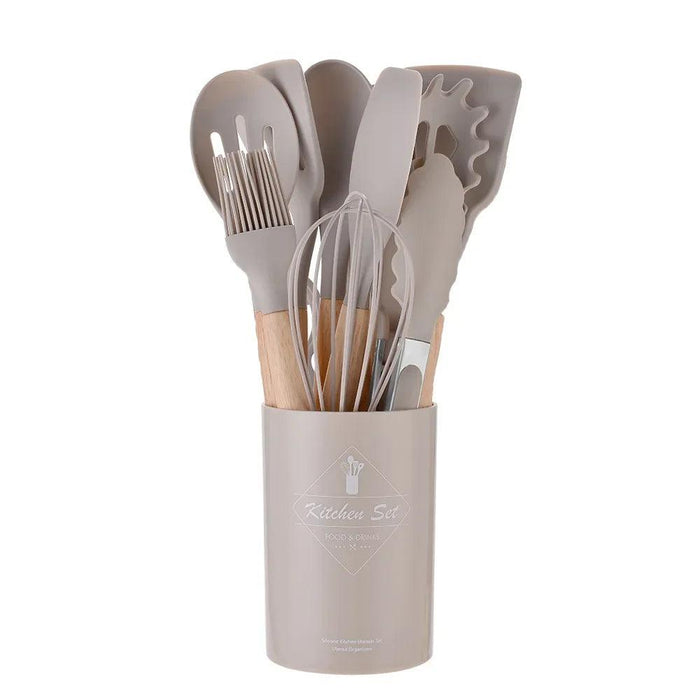 A set of khaki silicone kitchen utensils with wooden handles in a matching holder.