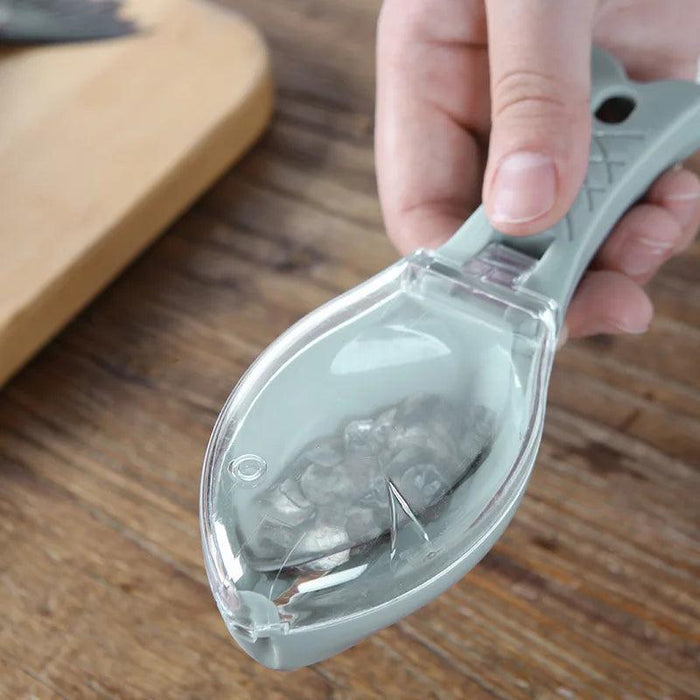 Close-up of a fish scaler tool with a built-in cover, being held in hand, showing collected fish scales inside.