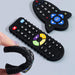 Close-up of three black silicone teethers shaped like remote controls, with one being bent in a hand.