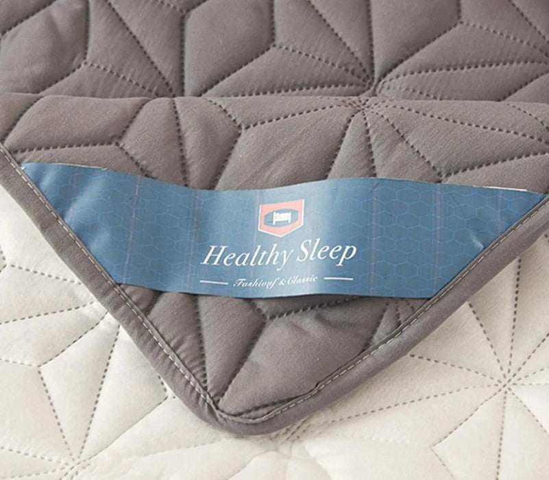 Close-up of the corner of the gray quilted mattress cover pad showing a label that reads "Healthy Sleep."