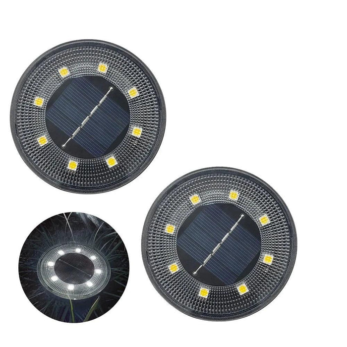 2 round solar-powered garden lights with a dark frame and multiple LED lights arranged in a circular pattern around a solar panel in the center. An inset shows the light illuminated at night, emitting a white glow.