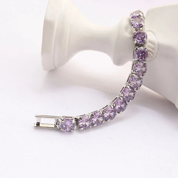 Silver tennis bracelet with purple stones displayed on a white surface.