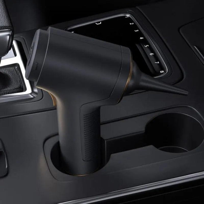 Shows the vacuum placed in a car's cup holder, highlighting its compact size and portability for car cleaning.